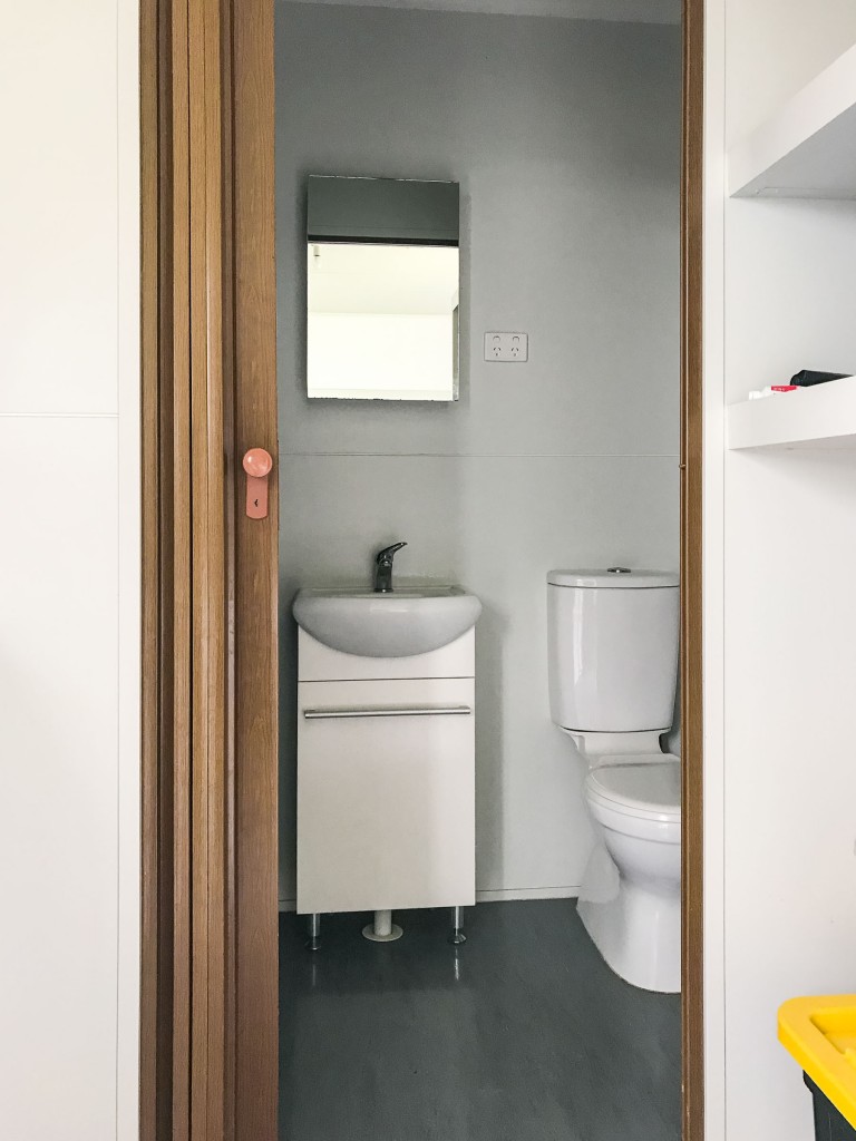 Toilet and vanity basin with ensuite door open. There is a mirror and powerpoint in the bathroom