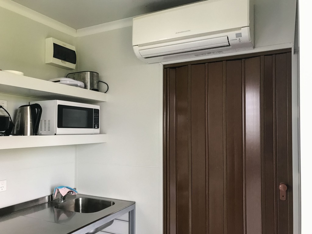 Kitchenette showing reverse cycle air conditioner/heater with door to ensuite closed
